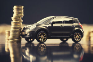 Kleines schwarzes Auto neben einem hohen Stapel Goldmünzen, symbolisiert Autofinanzierung oder Fahrzeugkosten