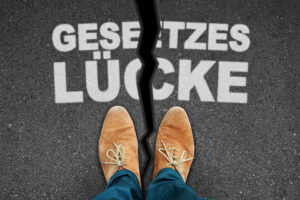 Person steht an einem Riss im Asphalt mit der Aufschrift „Gesetzeslücke