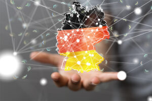 Digitale Vernetzung Deutschlands: Eine Hand hält ein schwebendes Hologramm der Deutschland-Karte in Nationalfarben mit Netzwerkknoten